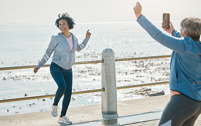 Buy stock photo Phone, friends picture and senior woman smile at beach with silly pose at sea for fitness. Exercise, mobile and photo for social media post on a ocean promenade walk for workout and friendship