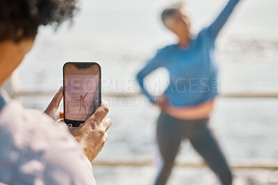 Buy stock photo Phone, fitness and photograph of woman at beach in silly pose at sea for senior friends. Exercise, mobile and picture for social media post on a ocean promenade walk for nature workout and friendship