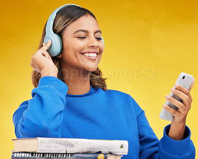 Buy stock photo Woman, student and phone in studio with headphones, books and thinking with smile by yellow background. Gen z girl, smartphone and streaming subscription for music app, thinking and studying economy