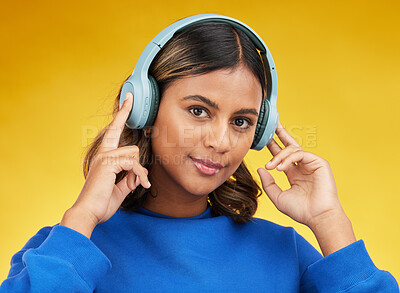 Buy stock photo Headphones, portrait and young woman in a studio listening to music, playlist or album with confidence. Happy, smile and headshot of female model streaming song or radio isolated by yellow background