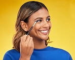 Woman, makeup and brush with skincare, thinking or self care on a yellow studio background. Female person, smile or model with cosmetic tool, luxury or foundation with mindset, aesthetic or eyeshadow