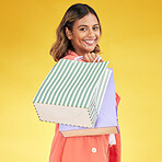 Portrait, woman and smile with shopping bag in studio for fashion, retail deal or financial freedom on yellow background. Indian customer, gift bags and discount at boutique, store or sales promotion