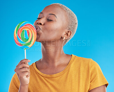 Buy stock photo Lollipop, kiss and a woman with candy in studio for sweets, rainbow and creative advertising. Happy and funny black female person isolated on a blue background with love of sugar, freedom and color