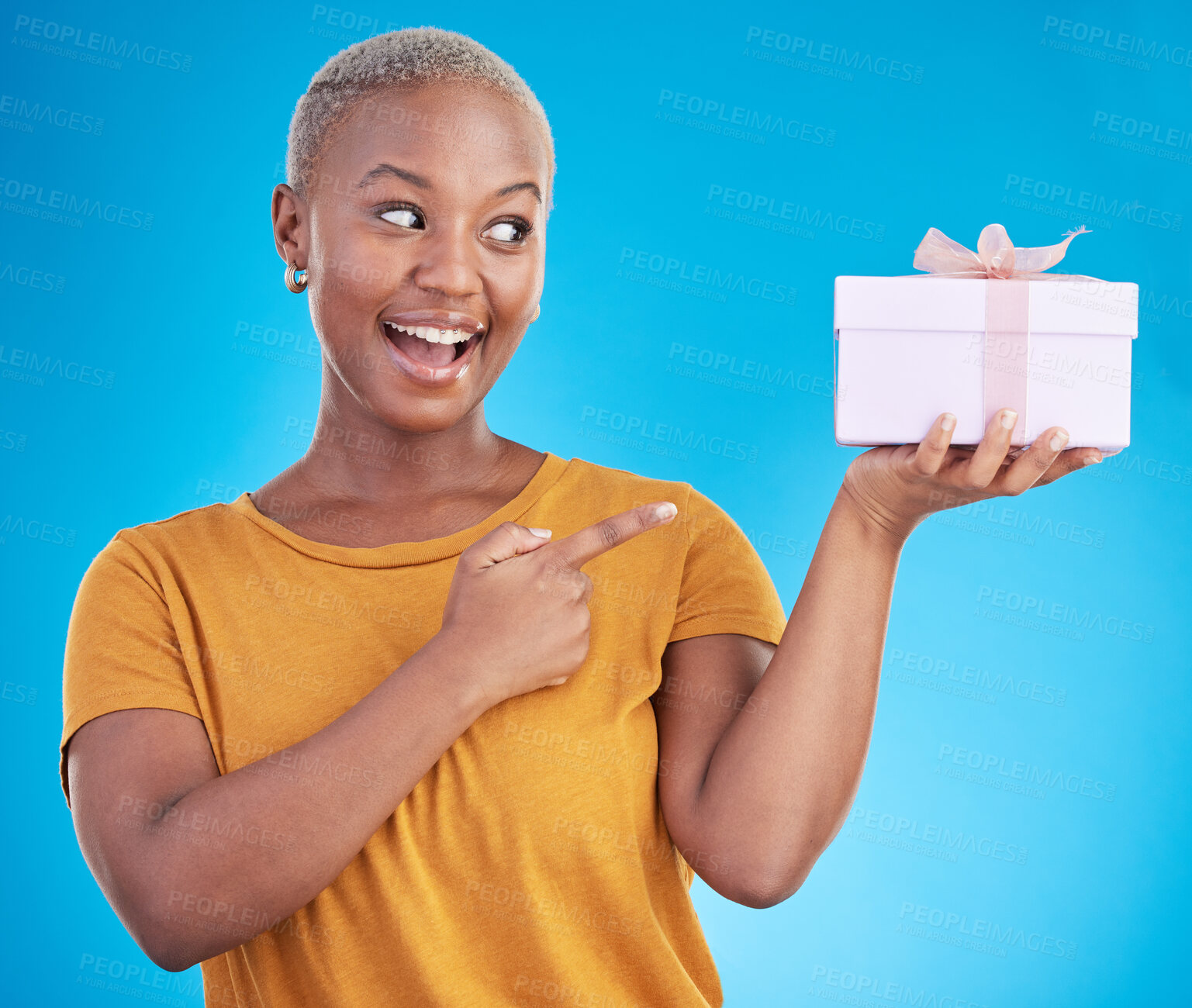 Buy stock photo Gift, excited black woman and pointing at box in studio isolated on a blue background. Promotion, happy or African person with present for party, celebration of holiday or birthday for giveaway prize