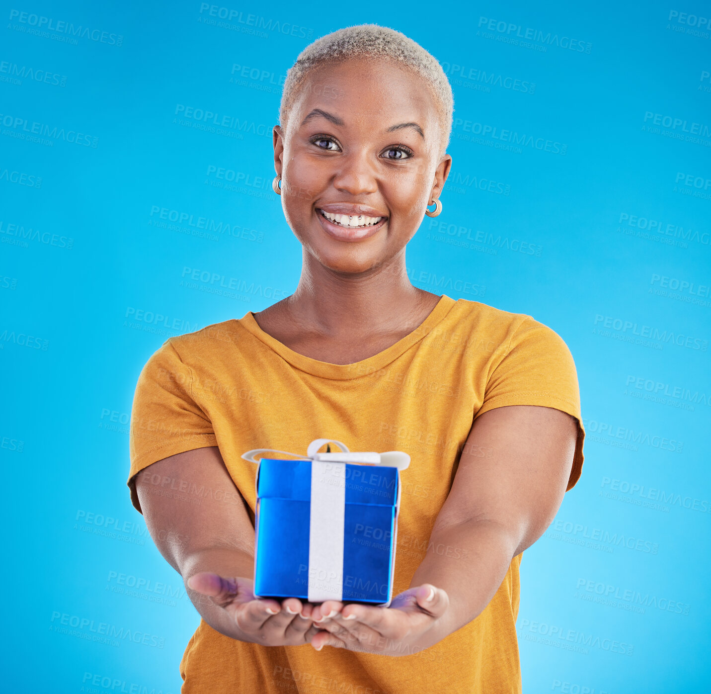 Buy stock photo Portrait, gift and happy black woman with giveaway in studio isolated on a blue background. Face, giving and person with present box for party, celebration or birthday package for offer of donation