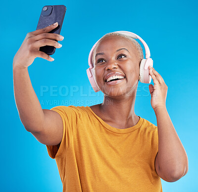 Buy stock photo Woman, selfie and headphones listening to music, audio streaming and social media influencer on blue background. Young african person on mobile video call and profile picture or photography in studio
