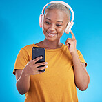 Woman, headphones and phone listening to music, audio streaming service and social media on a blue background. Young african person or influencer with electronics, techno or radio on mobile in studio