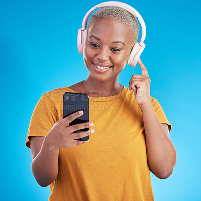 Buy stock photo Woman, headphones and phone listening to music, audio streaming service and social media on a blue background. Young african person or influencer with electronics, techno or radio on mobile in studio