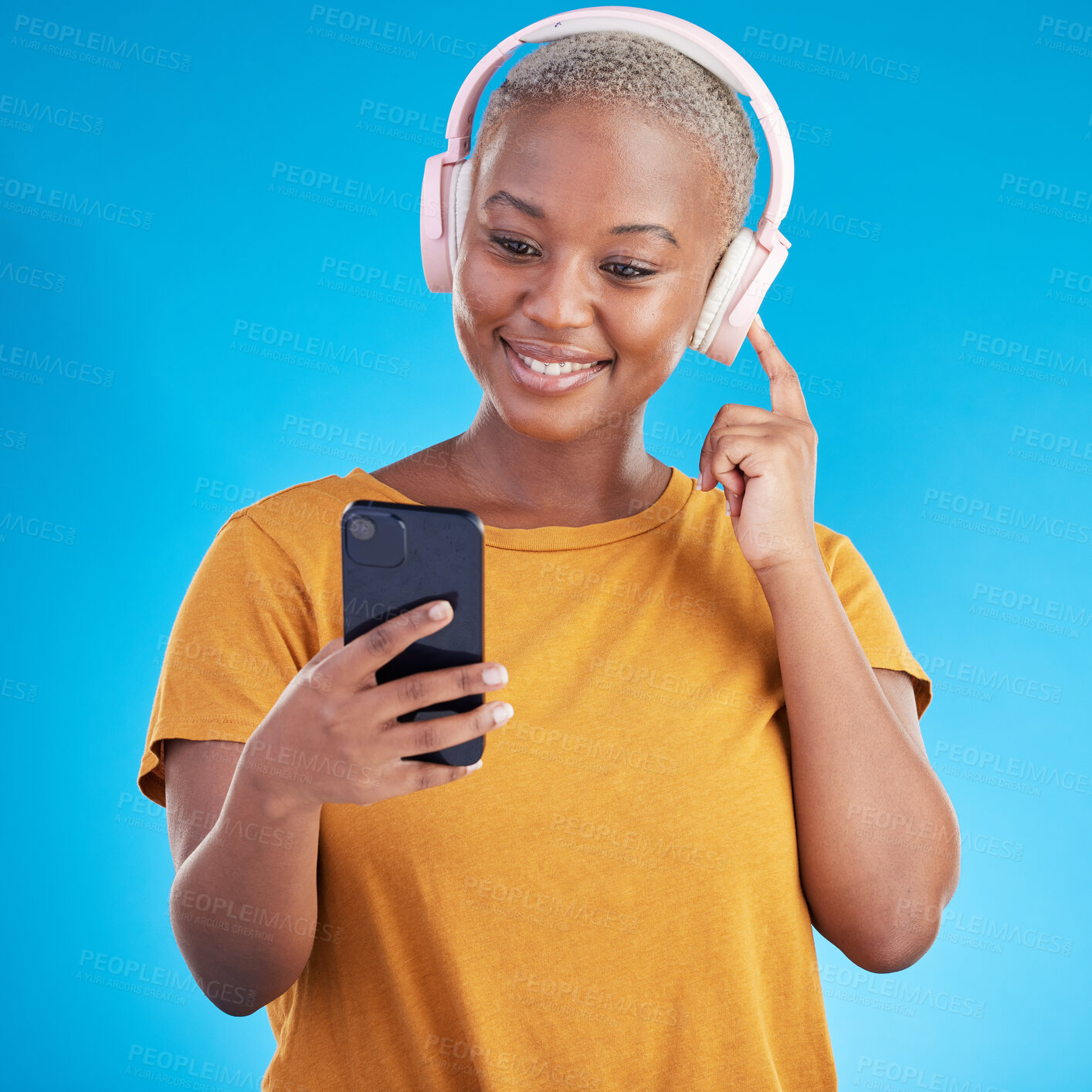 Buy stock photo Woman, headphones and phone listening to music, audio streaming service and social media on a blue background. Young african person or influencer with electronics, techno or radio on mobile in studio