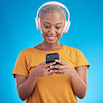Woman, smartphone and headphones listening to music, audio streaming service or social media on blue background. Young african person or influencer chat on mobile for podcast subscription in studio