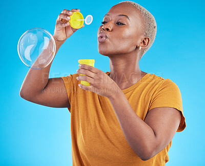 Buy stock photo African, woman and blowing bubbles in studio, blue background or fun party celebration with liquid soap or toy. African girl, person and relax with happy, joyful or creative bubble for calm break