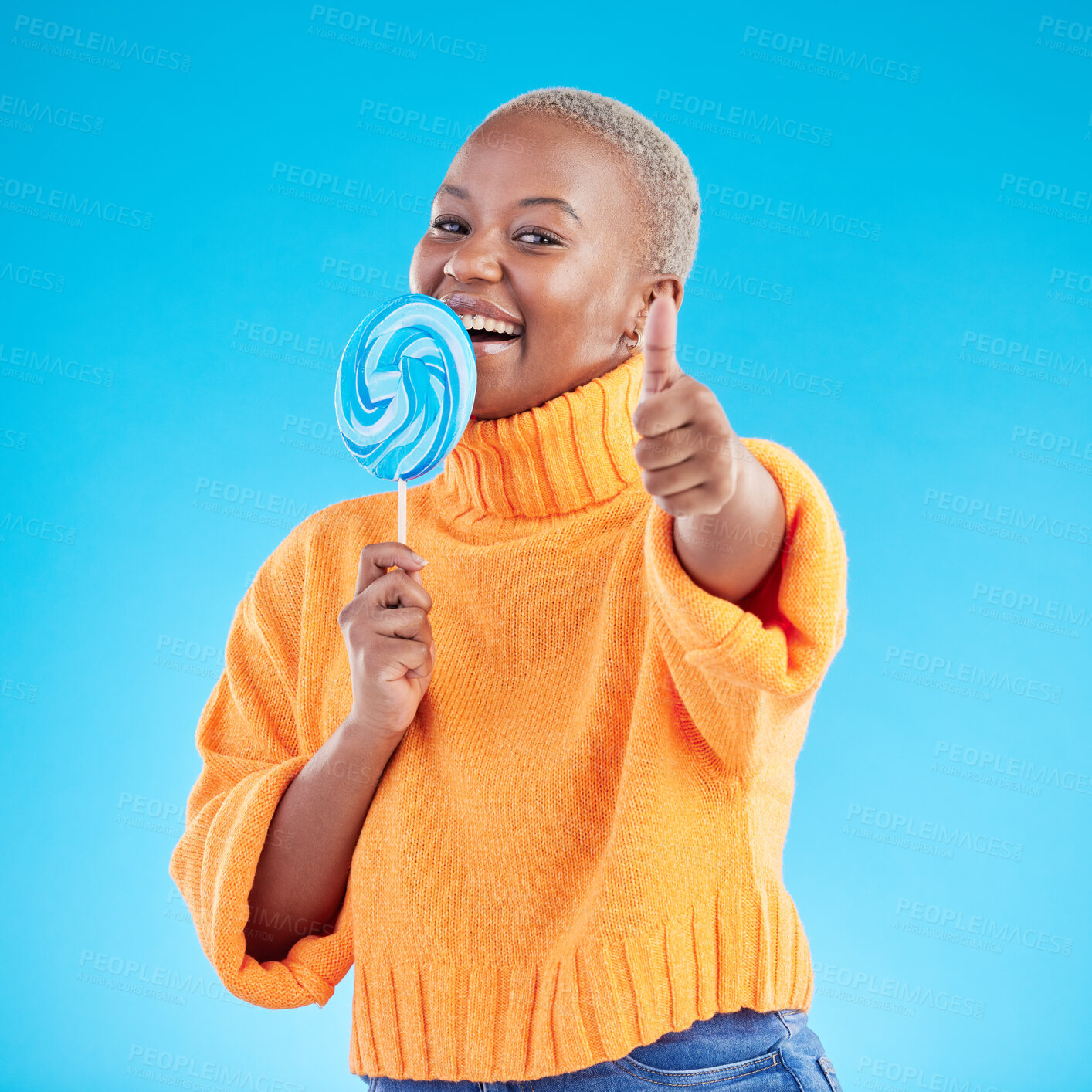 Buy stock photo Thumbs up, lollipop and black woman in portrait with candy in studio isolated on a blue background. African person, happy face and sweets, dessert and sugar food with like hand sign for excellence