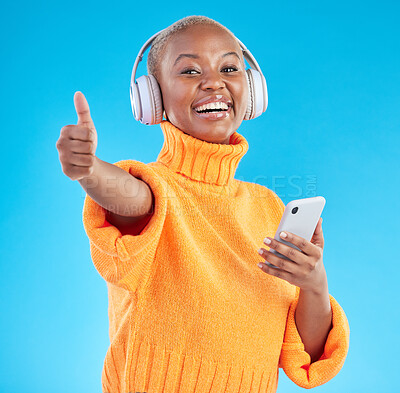 Buy stock photo Headphones, portrait or black woman with thumbs up for mobile feedback on a blue background. Smile, radio or happy girl with like hand sign for success, listening or streaming to review a podcast