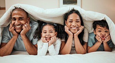 Buy stock photo Happy, love and portrait of a family in bed with a blanket relaxing, resting and bonding at home. Happiness, smile and young children laying with their mother and father in the bedroom of their house