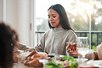 Woman, praying and holding hands at family dinner at thanksgiving celebration at home. Food, female person and eyes closed at a table with religion, lunch and social gathering on holiday in house