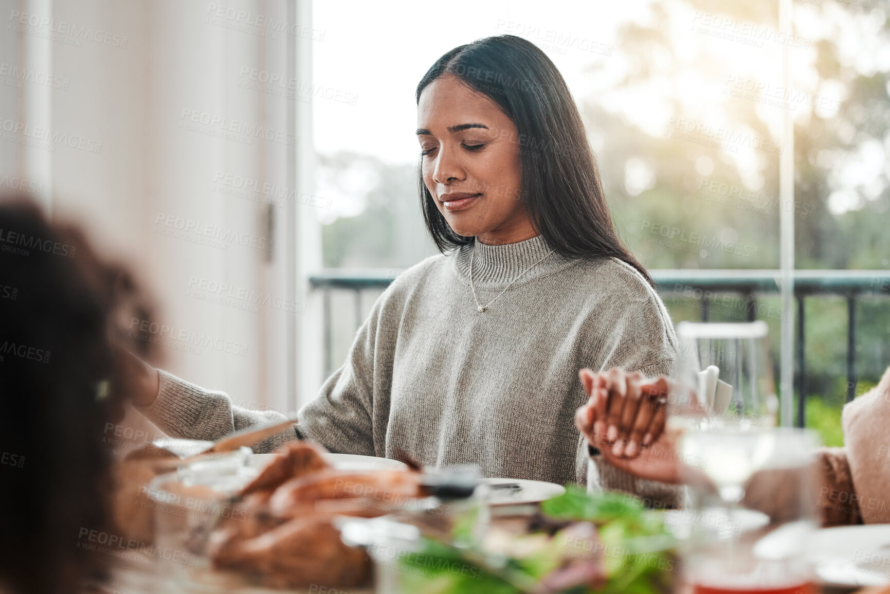 Buy stock photo Woman, praying and holding hands at family dinner at thanksgiving celebration at home. Food, female person and eyes closed at a table with religion, lunch and social gathering on holiday in house