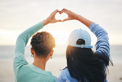 Buy stock photo Love, beach and lesbian couple with heart hands at sunset, summer holiday adventure or date together. Lgbt women, bonding and relax on ocean vacation with romance, pride and happy partner in nature.