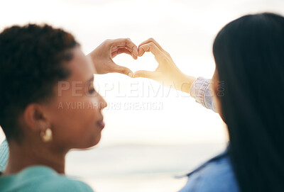 Buy stock photo Love, beach and lesbian couple with heart hands from back at sunset, summer holiday adventure or date together. Lgbt women, bonding and ocean vacation with romance, pride and happy partner in nature.