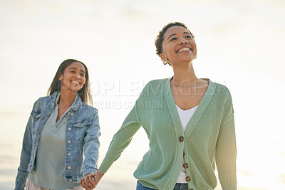 Buy stock photo Love, ocean and happy lesbian couple holding hands, walking together and sunset holiday adventure. Lgbt women, bonding and relax on beach vacation with romantic date, pride and smile on nature travel