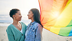 Lesbian couple, pride flag and freedom hug at beach for romance, happy or care in nature. Rainbow, love and women at the ocean embrace lgbt, gay or partner pride, date or romantic relationship moment