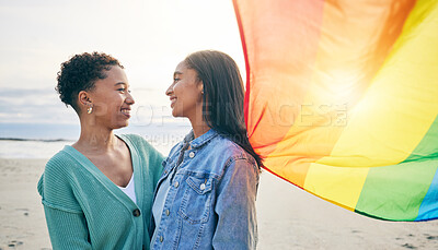 Buy stock photo Lesbian couple, pride flag and freedom hug at beach for romance, happy or care in nature. Rainbow, love and women at the ocean embrace lgbt, gay or partner pride, date or romantic relationship moment