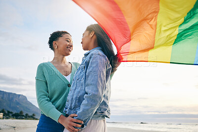 Buy stock photo Pride, flag and lesbian couple at the beach for travel, freedom and bond, care and happy in nature together. Rainbow, love and women on ocean vacation embrace lgbt, partner or gay, date or acceptance