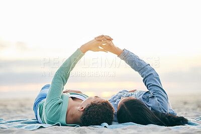 Buy stock photo Love, ocean and lesbian couple on blanket holding hands on sand, summer and sunset holiday adventure. Lgbt women, bonding and relax on beach picnic date with romance, pride and happy lying in nature.