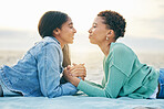 Love, ocean and sunset, lesbian couple on blanket together, holding hands on sand and holiday adventure. Lgbt women, bonding and relax on beach vacation with romance, pride and happy lying in nature.