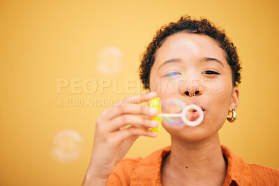 Buy stock photo Portrait, blowing bubbles and woman in studio for fun, playful or freedom of expression on yellow background. Bubble, stress relief and face of lady model with liquid soap for celebration or weekend