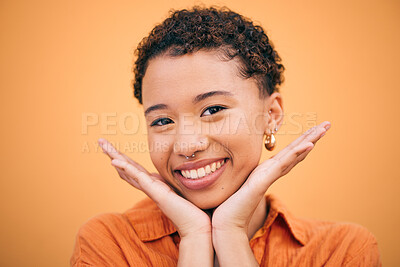 Buy stock photo Happy, woman and hands on face in studio with smile and confidence feeling cute. Orange background, young portrait and African female person with trendy, modern and student fashion of gen z glow