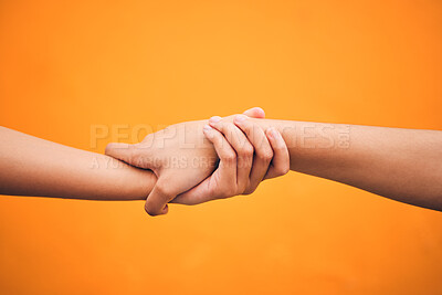 Buy stock photo Holding hands, studio and closeup for support, help and care for teamwork by orange background. People, friends and together for solidarity, link and connection with synergy, partnership and strong