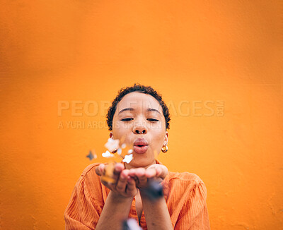 Buy stock photo Blowing, petals and face of woman on orange background for natural beauty, skincare and romance. Flowers, happy and female person with floral confetti for cosmetics, makeup and satisfaction in studio