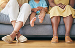 Legs, gay couple and a family on a home sofa for security, quality time and love. Feet of women or lesbian parents and a young child together in a living room with love, care and support for adoption