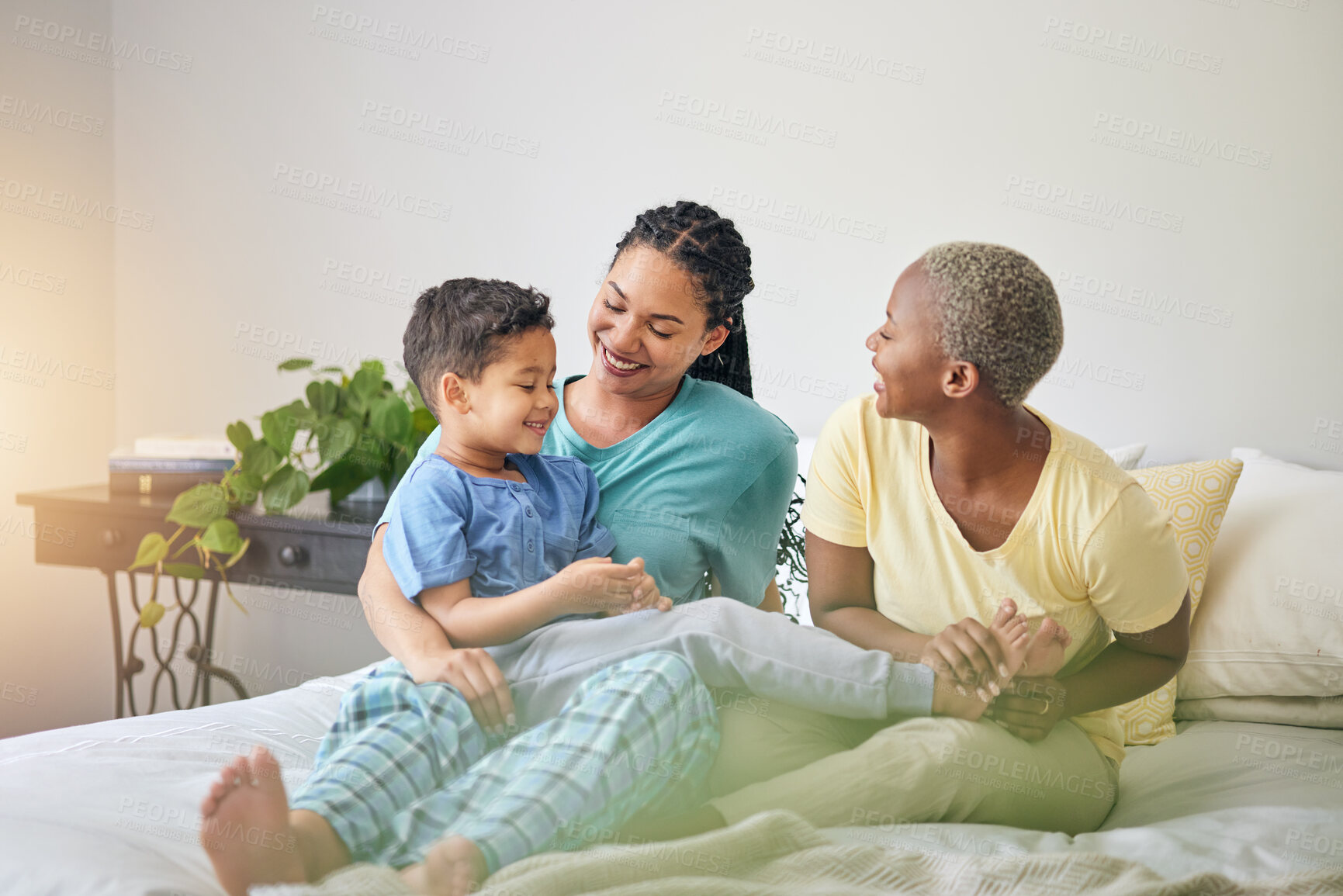 Buy stock photo Gay family, morning and playing on bed in home bedroom for bonding, quality time and love. Adoption, lesbian or LGBTQ women or interracial parents and a happy kid to wake up with fun, care and laugh