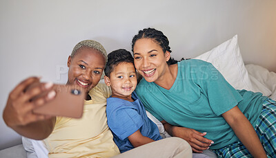 Buy stock photo Gay, happy family and selfie in bed with foster boy child and relax at home. Adoption, lesbian couple and lgbt women on social media, smile for profile picture, blog or post in bedroom on the bed