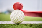 Closeup, grass and a stick and ball for hockey, sports and training on a field for a game. Fitness, exercise and gear for a match, workout or competition on a turf or ground of a park for cardio