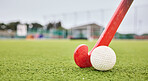 Field, sports and a ball and a stick for hockey, fitness and training in the morning. Closeup, ground and gear or equipment for a competition, game or tournament at a stadium or turf on bokeh