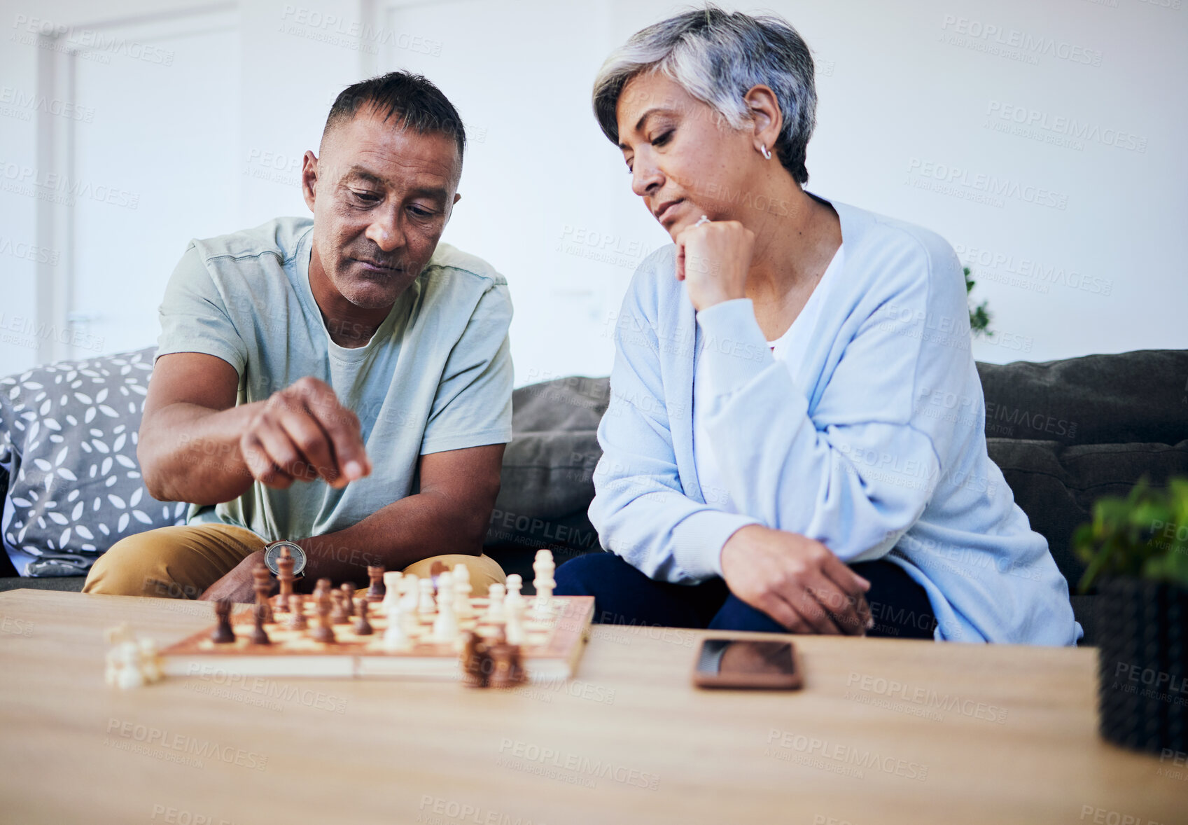 Buy stock photo Senior couple, chess match and home with thinking, strategy and mindset for brain power, relax and bonding. Elderly woman, man and sofa with board game, ideas and brainstorming for challenge in house