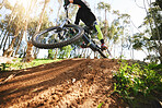 Bike, jump and dirt with speed in low angle for sports, race and adventure in summer, woods or nature. Extreme cycling, person and outdoor for trail, competition or challenge for fitness in forest