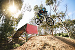 Bike, jump and man with ramp, outdoor and speed for sports, race or adventure in summer, woods or nature. Extreme cycling, person and outdoor for trail, competition or challenge for fitness in forest