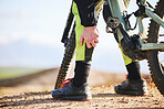 Hand, cycling and leg pain with a person on a bike outdoor on a dirt track for fitness or exercise. Sports, training injury injury and an athlete on a bike with a medical emergency or accident