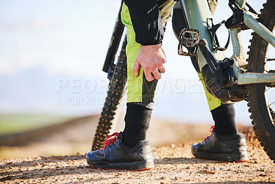 Buy stock photo Hand, cycling and leg pain with a person on a bike outdoor on a dirt track for fitness or exercise. Sports, training injury injury and an athlete on a bike with a medical emergency or accident