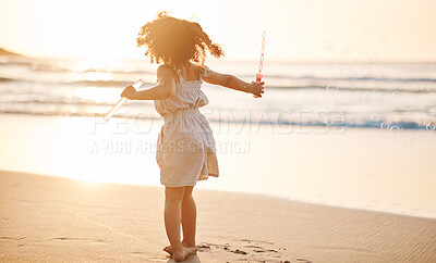 Buy stock photo Girl child, bubbles and back by beach in sunset, playing and freedom by waves, games and ocean vacation. Young female kid, plastic toys and soap with water in summer sunshine by sea for holiday