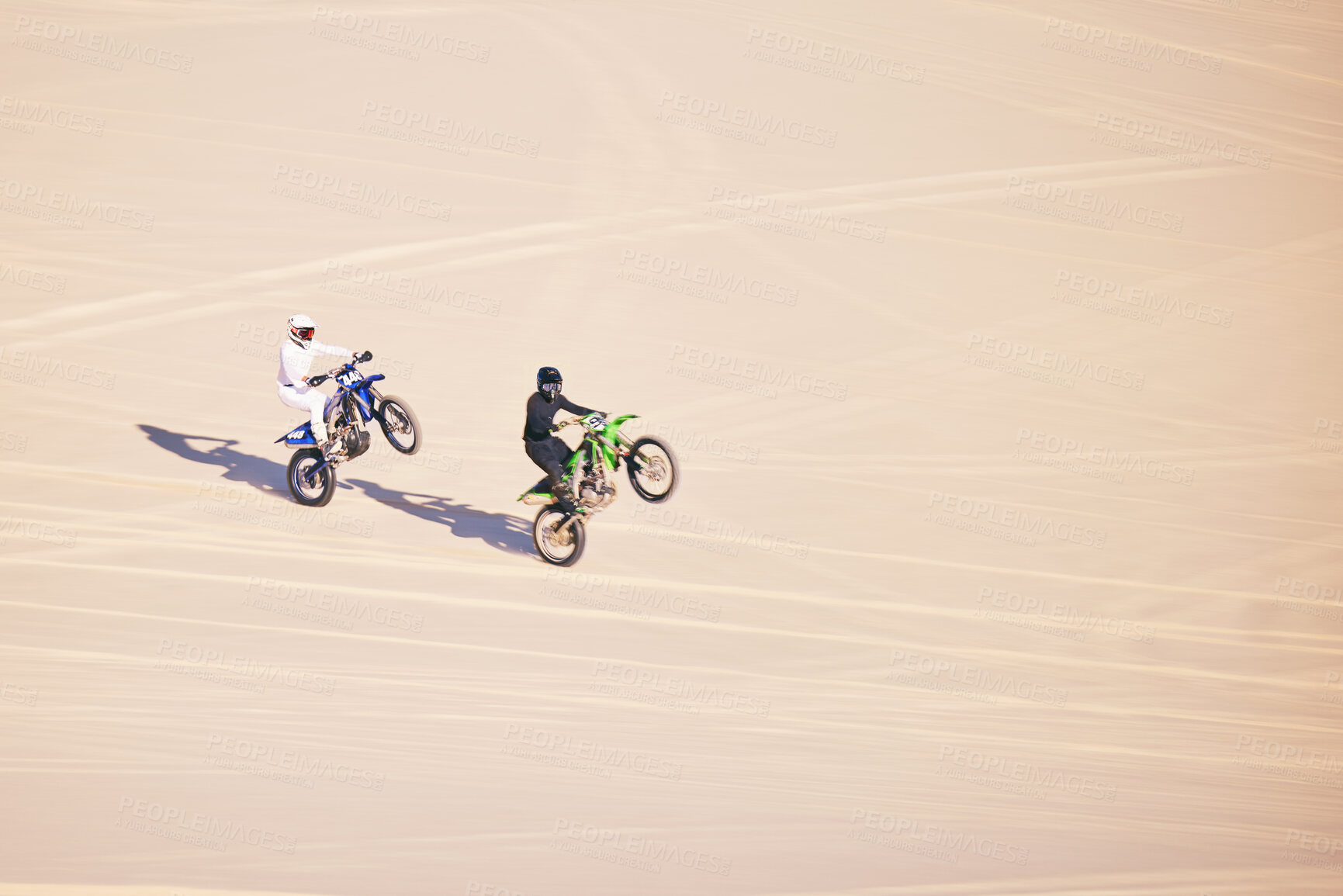 Buy stock photo Motorcycle, sand and sports with people in the desert for adrenaline, adventure or training in nature. Bike, summer and freedom with friends outdoor together to wheelie while riding on mockup space