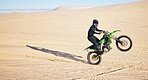 Motorcycle, sand and space with a man in the desert for adrenaline, adventure or training in nature. Energy, summer and balance with an athlete riding a bike for sports training in a remote location