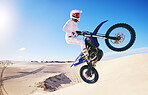 Jump, moto cross and man on motorcycle on sand for adrenaline, adventure and freedom in desert. Action, extreme sports and male person on bike on dunes for training, exercise and race or challenge