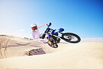 Sand, moto cross and man in air with motorbike for adrenaline, adventure and freedom in desert. Action, extreme sports and male person on bike on dunes for training, exercise and race or challenge