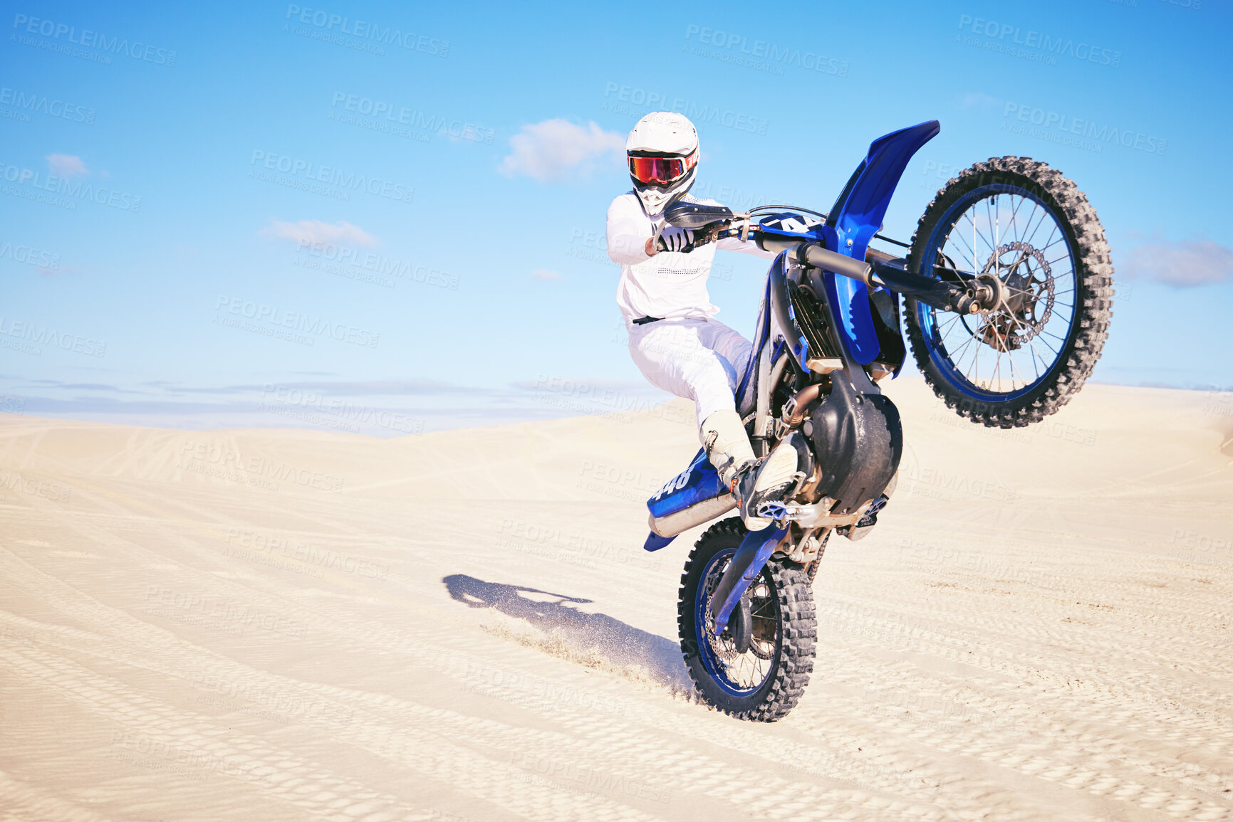Buy stock photo Bike, freedom and balance with a man in the desert for fitness or an adrenaline hobby on a blue sky. Motorcycle, training and summer with a male sports athlete riding a vehicle in Dubai for energy