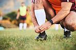 Rugby, hands and athlete tie shoes to start workout, exercise or fitness. Sports, player and man tying boots in training preparation, game or competition for healthy body or wellness on field outdoor