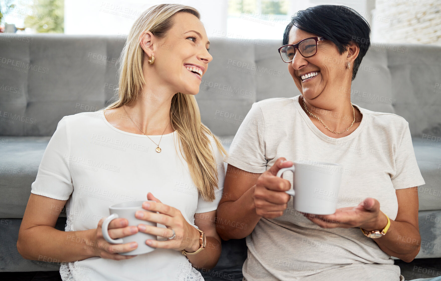 Buy stock photo Women friends, coffee and living room floor with smile, funny conversation and relax with care, diversity and love. Mature lady, happy and together with latte, espresso and comic laugh in home lounge